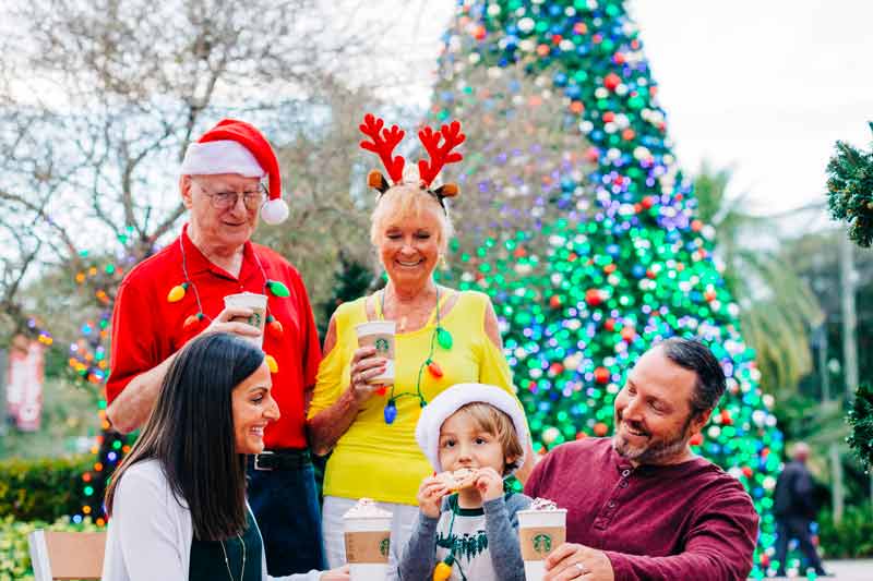 A family enjoys holiday treats while they gather by the huge Christmas tree at ZooTampa
